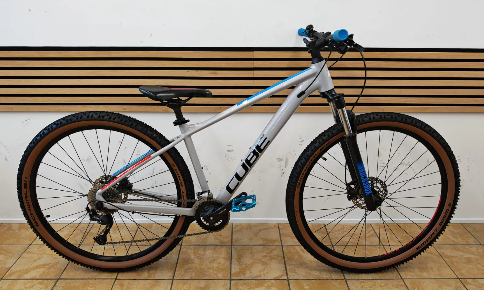 Cube Mountainbike in Grau mit blauen und roten Akzenten, RockShox-Federgabel und Smart-Sam-Reifen